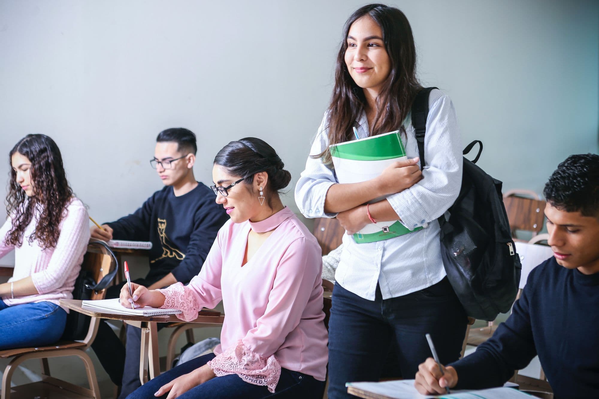 Teenage girl standing in class holdering her books.